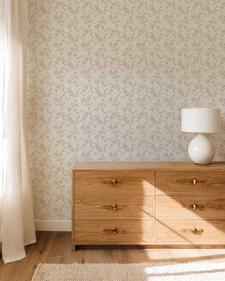 Wooden dresser with a lamp against a Blythe Cream & Pink Wallpaper