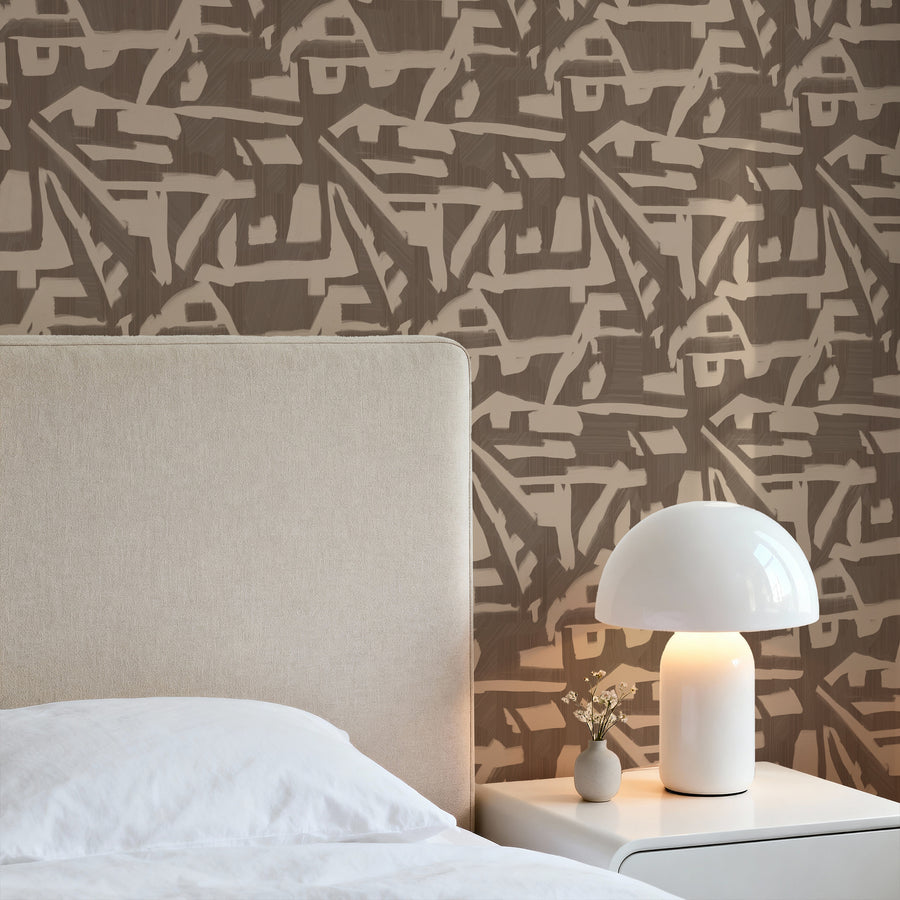 Bedroom with cream upholstered headboard and white mushroom table lamp featuring Abstract Brushstroke Wallpaper Taupe Brown by Petra Kohlmayr
