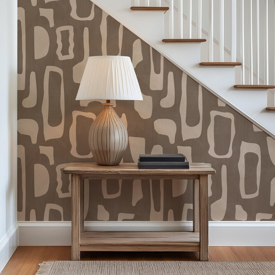 Entryway under staircase with wood console table and ceramic table lamp featuring Abstract Organic Shapes Wallpaper Beige Brown by Petra Kohlmayr