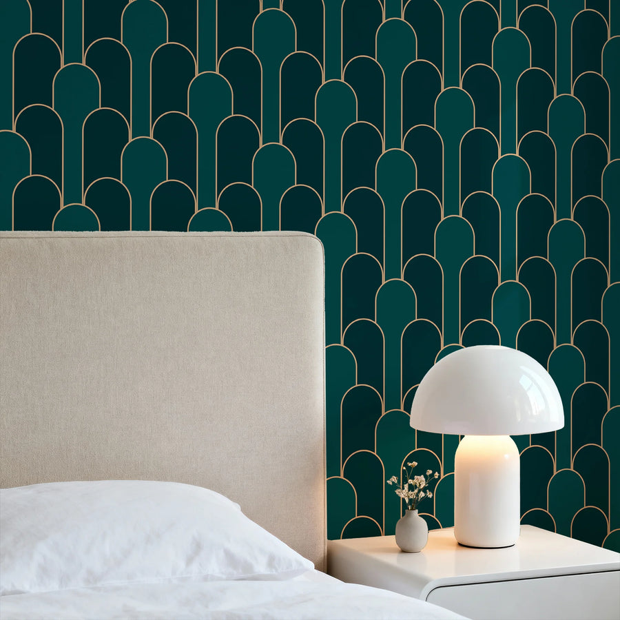Art Deco arch wallpaper in emerald green and gold in a bedroom behind a cream upholstered headboard