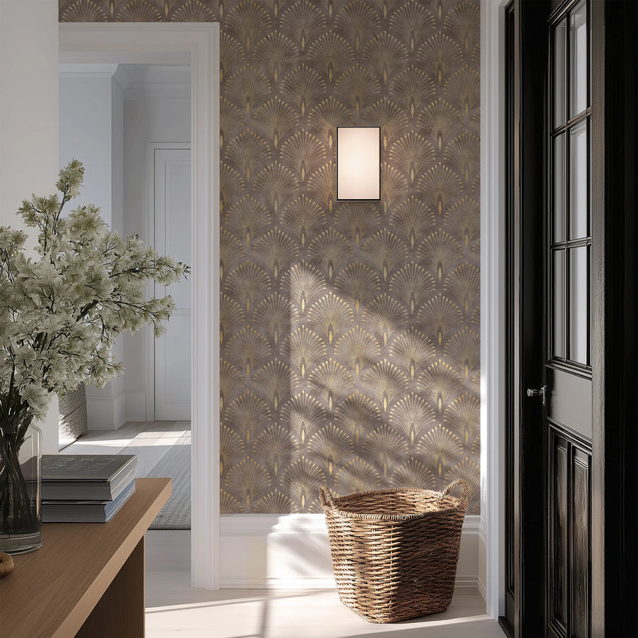 Art Deco fan wallpaper in brown and gold on an entryway wall beside a dark paneled door and wall sconce