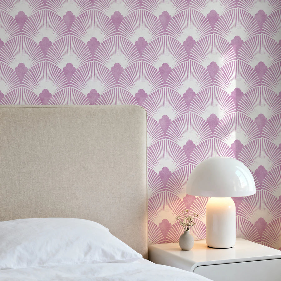 Pink mauve and white Art Deco scallop wallpaper in a bedroom behind a cream upholstered headboard