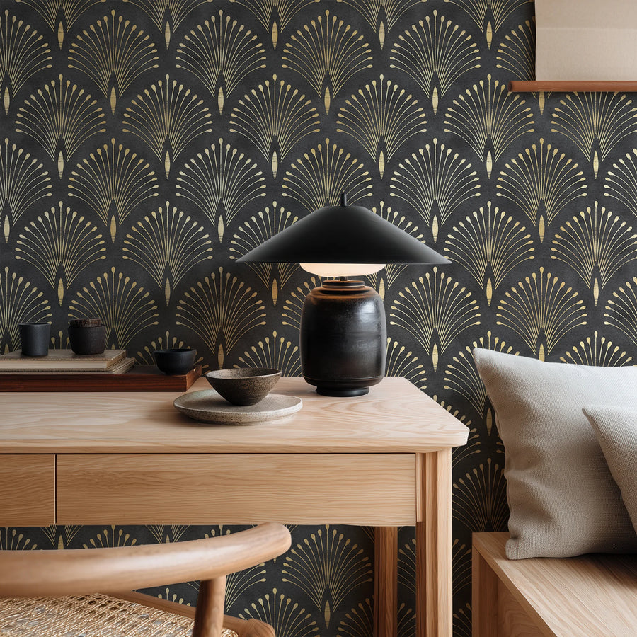 Art deco black and gold fan wallpaper behind a wood desk with a black lamp