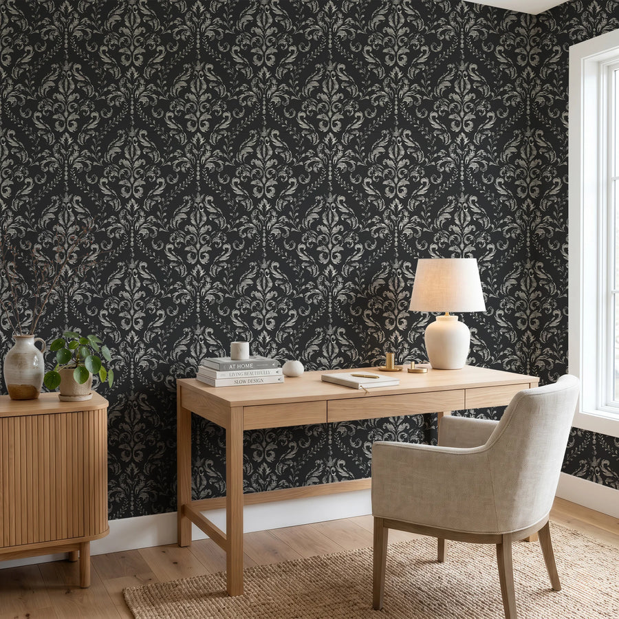 Black distressed damask wallpaper in a home office behind a wood desk