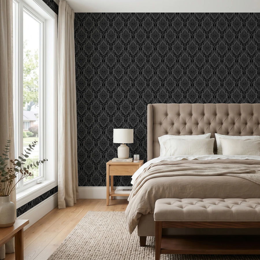 Black damask wallpaper in a bedroom behind a tufted headboard