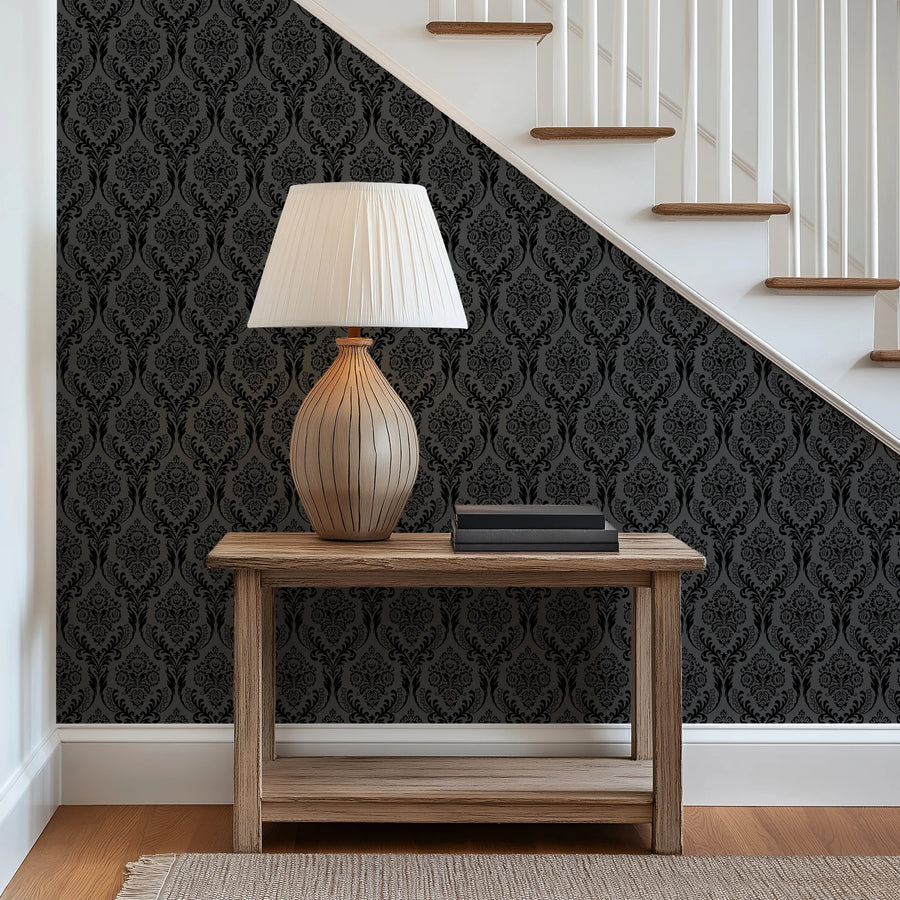 Black damask wallpaper on a stair landing behind a console table