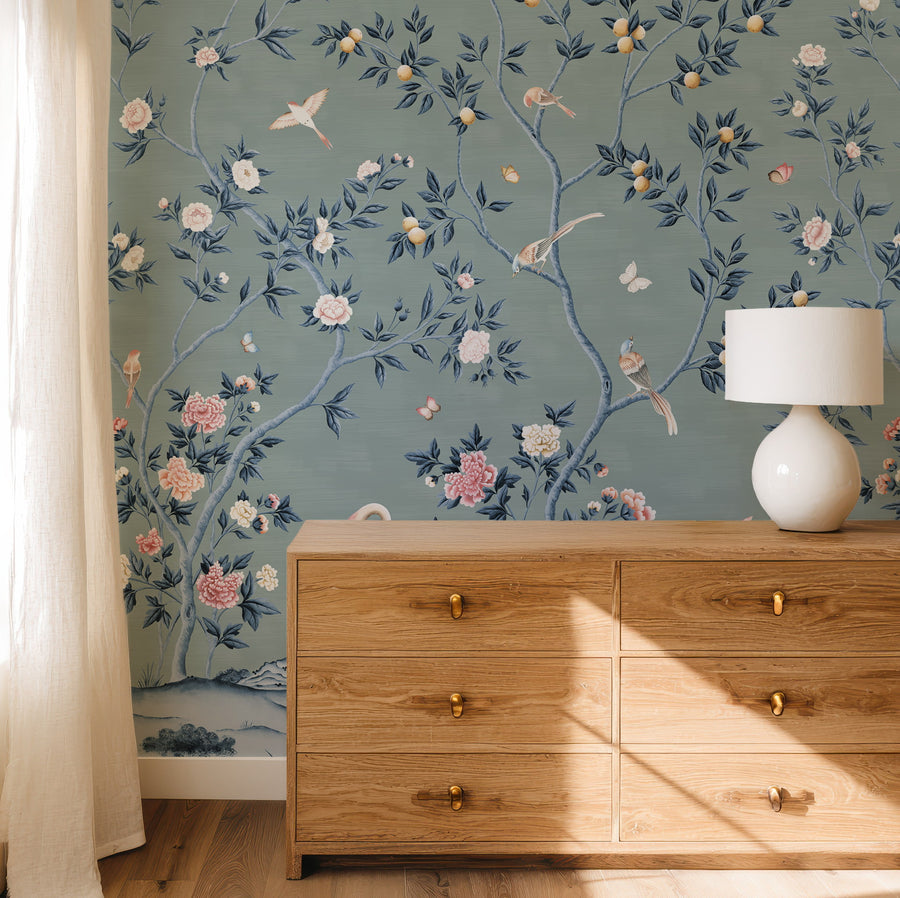 Blue chinoiserie crane mural in a bedroom behind a wood dresser and lamp