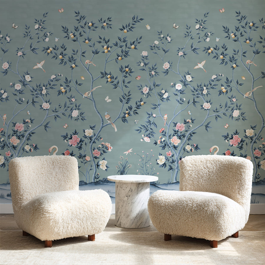 Blue chinoiserie crane mural in a sitting room behind two boucle armchairs