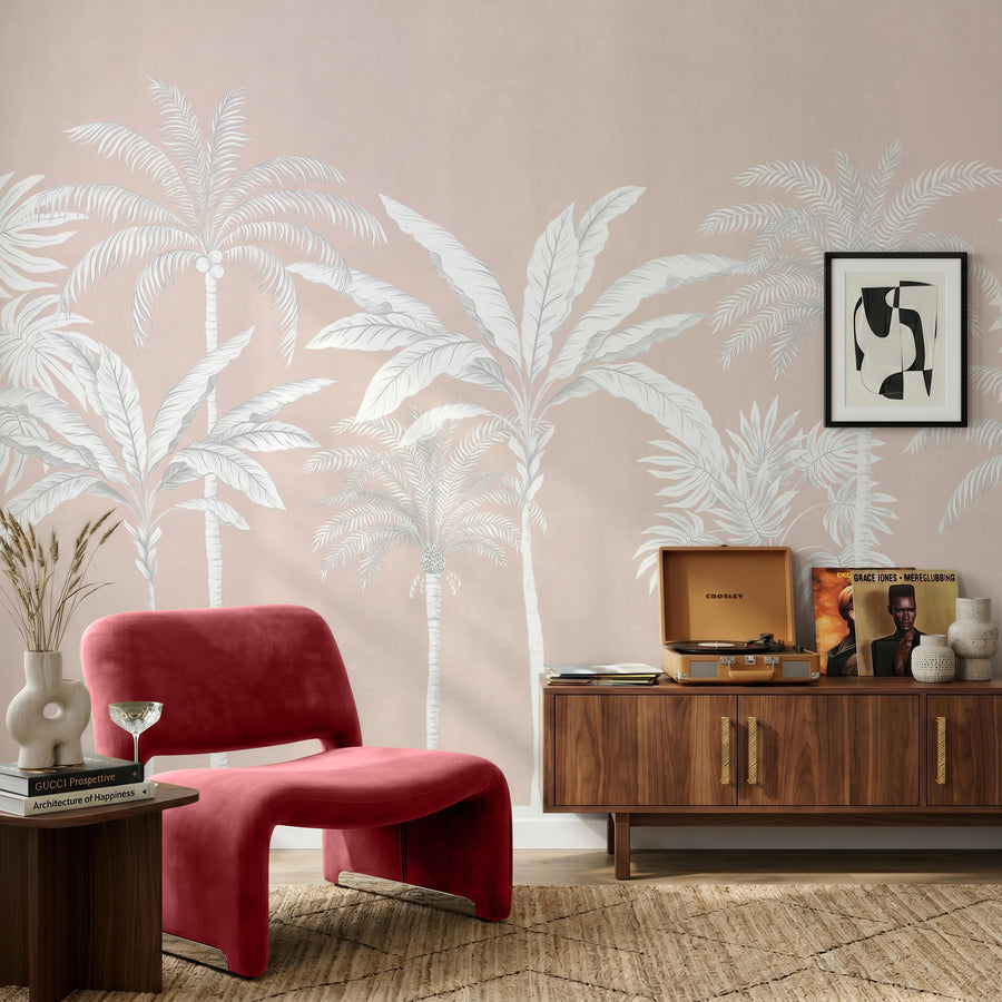 Blush pink palm tree wallpaper mural with white palms behind a red velvet chair and walnut credenza
