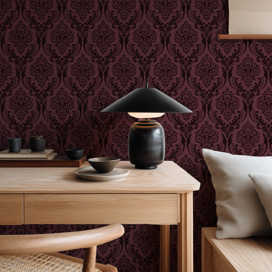 Burgundy damask wallpaper behind a console with a table lamp