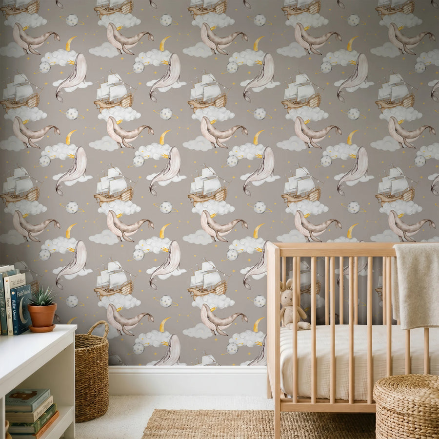 Whale and moon nursery wallpaper on taupe behind a wooden crib