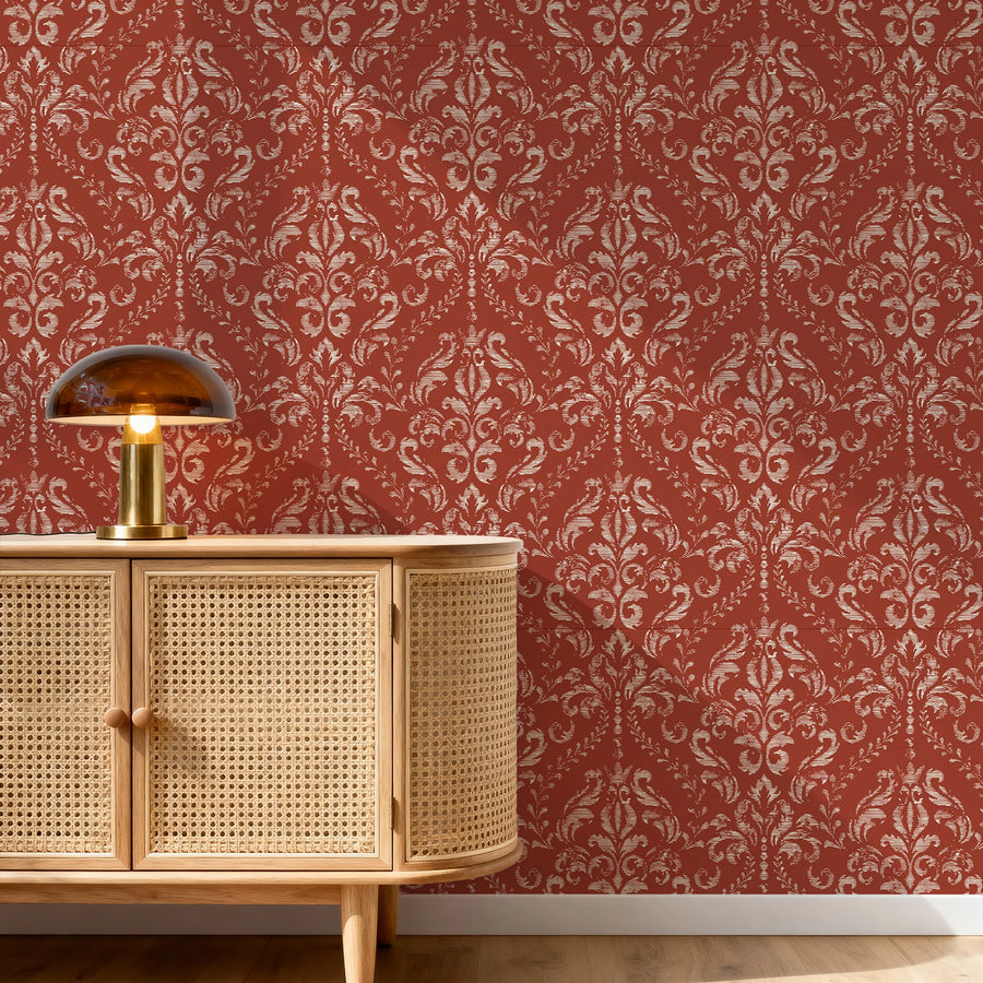 Classic red damask wallpaper behind a cane console with a table lamp