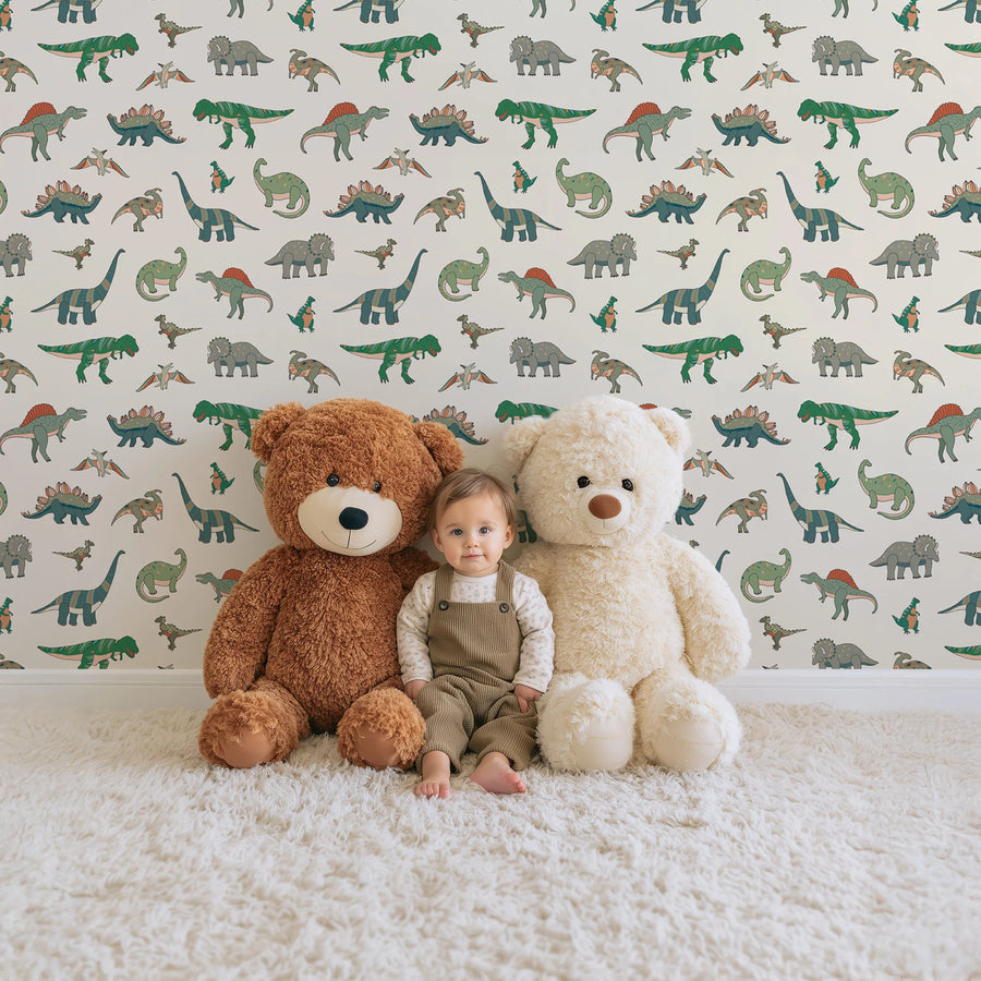 Green cartoon dinosaur kids wallpaper behind a toddler sitting between two teddy bears