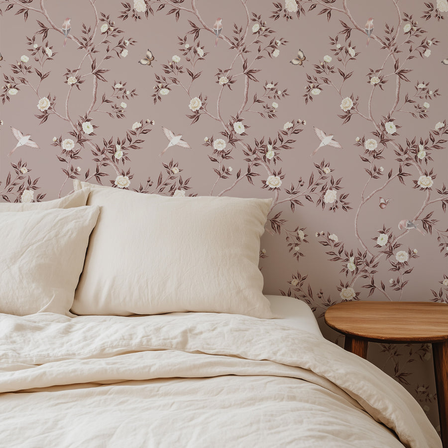 Bedroom with cream linen bedding and round wood nightstand featuring Dusty Rose Chinoiserie Hemma Wallpaper Floral Garden Birds by Maja Pitschmann
