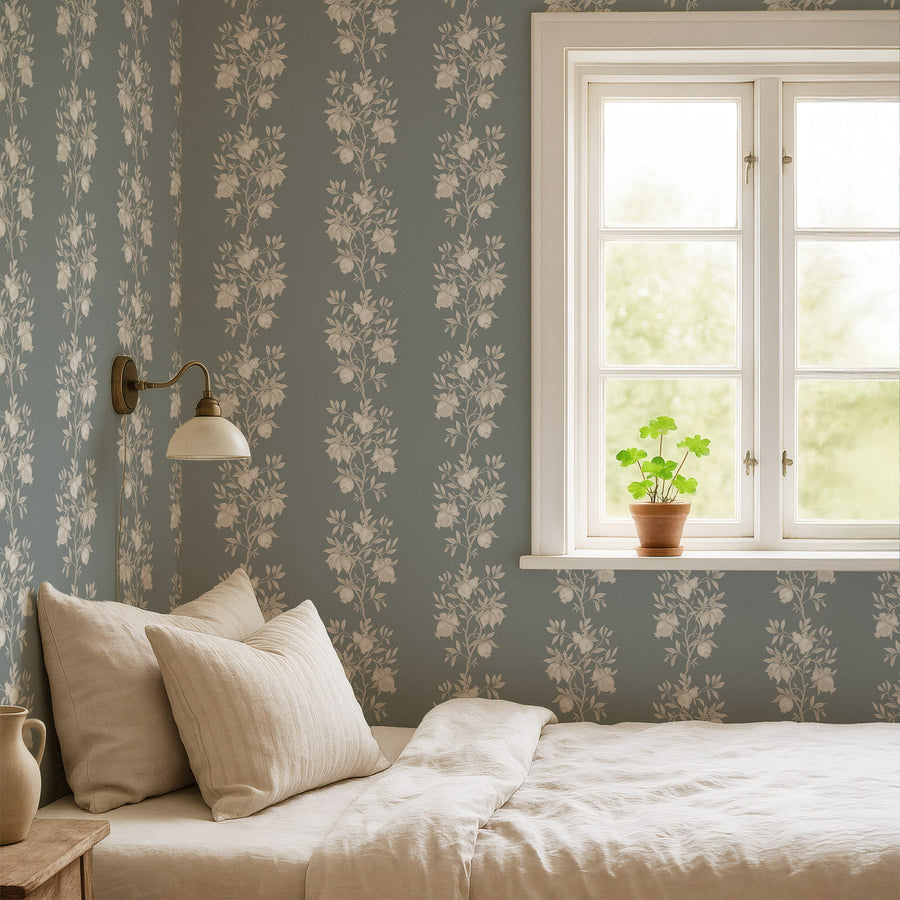Bedroom with cream pillows and wall sconce by a window featuring Elodie Chinoiserie Pomegranate Wallpaper Muted Blue accent wall