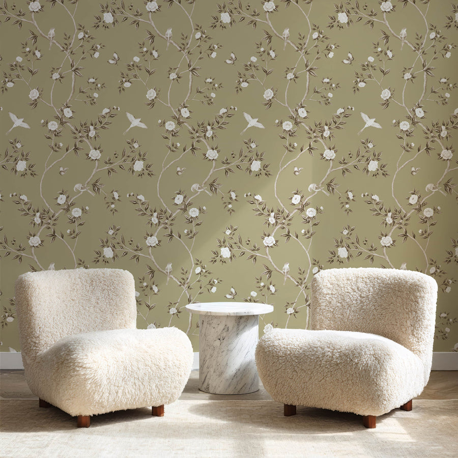 Lounge with two cream boucle chairs and side table featuring Green Chinoiserie Hemma Wallpaper Floral Garden Birds accent wall