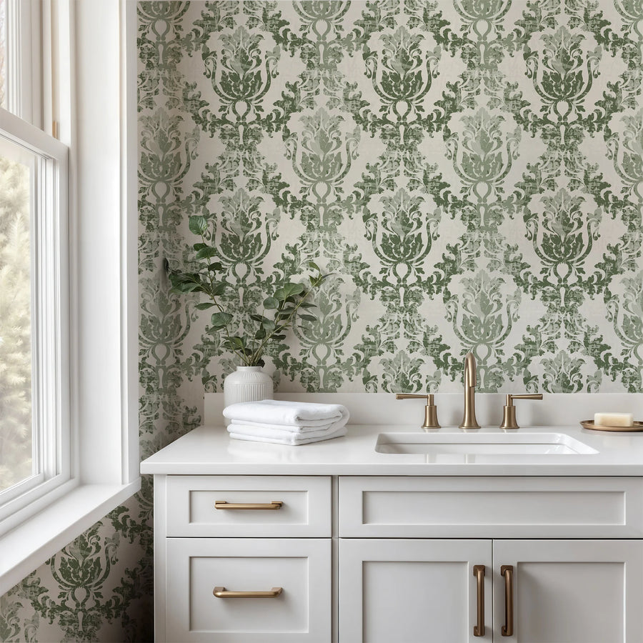 Sage green rococo damask wallpaper in a bathroom with a white vanity and gold fixtures