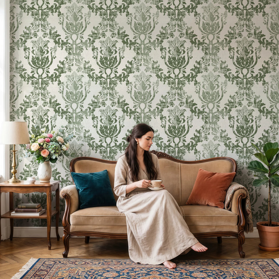 Sage green rococo damask wallpaper behind a sofa in a sitting room