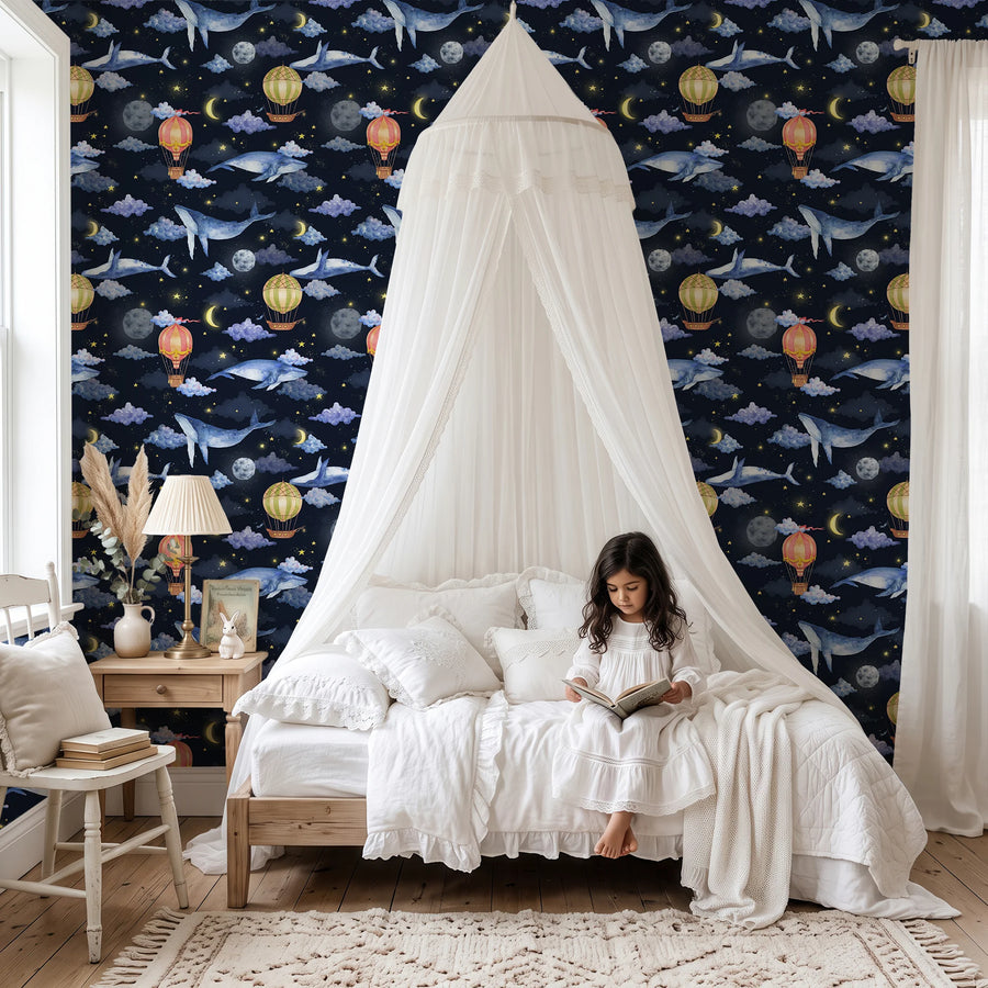Midnight navy hot air balloon and whale wallpaper behind a canopy bed in a girl's bedroom