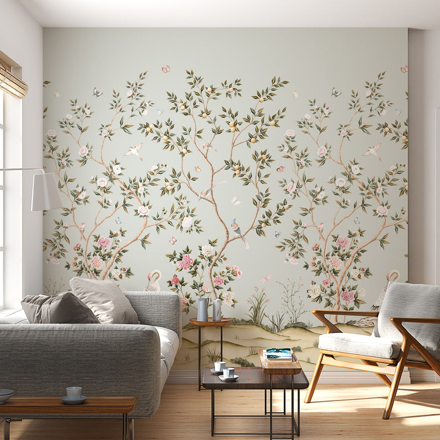 Light blue chinoiserie wallpaper mural with cranes and blossoms in a living room behind a grey sofa