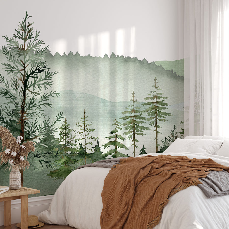 Misty sage green mountain wall mural with pine trees behind a bed with a rust throw and cream linen