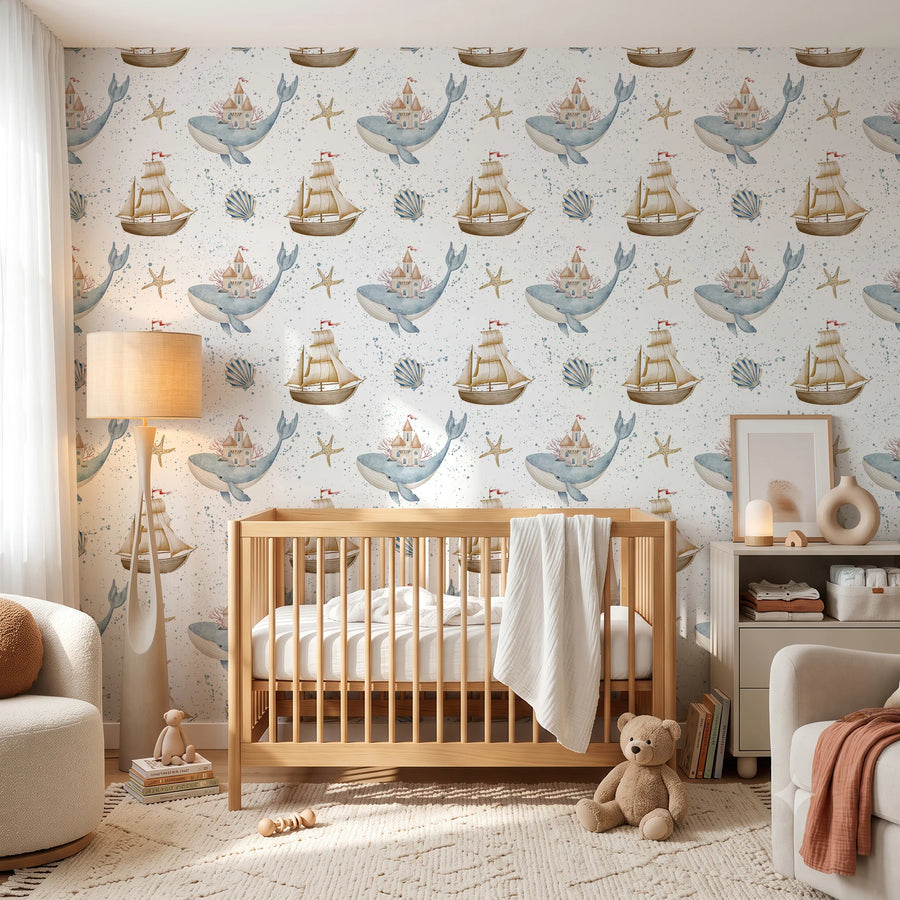 Nautical nursery wallpaper with whales and sailboats behind a wooden crib