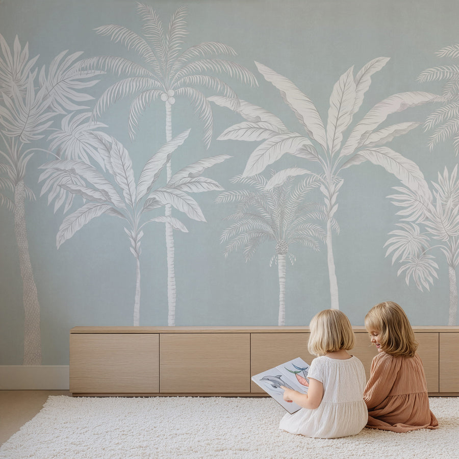 Pastel blue palm tree mural in a playroom with children reading on the floor