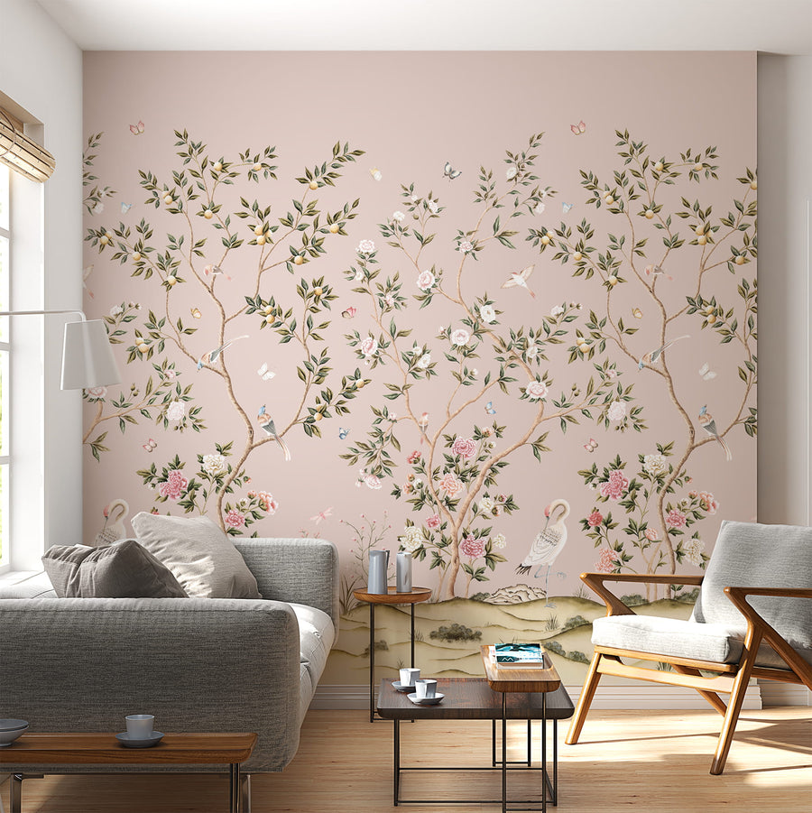 Pink chinoiserie wallpaper mural with cranes and blossoms in a living room behind a grey sofa