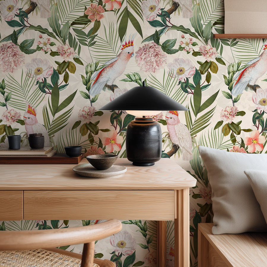 Pink cockatoo tropical floral wallpaper behind a wood console with a table lamp