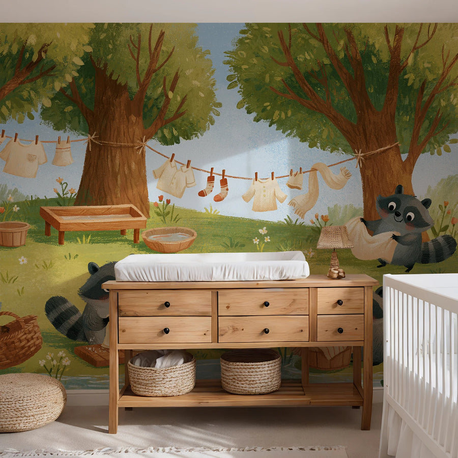 Raccoon laundry day forest mural behind a wooden dresser with a changing pad in a nursery