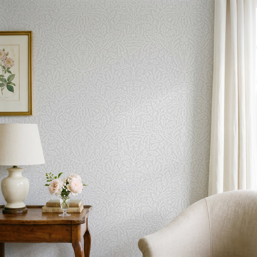 William Morris Acorn grey wallpaper behind a wood console with a lamp and framed art