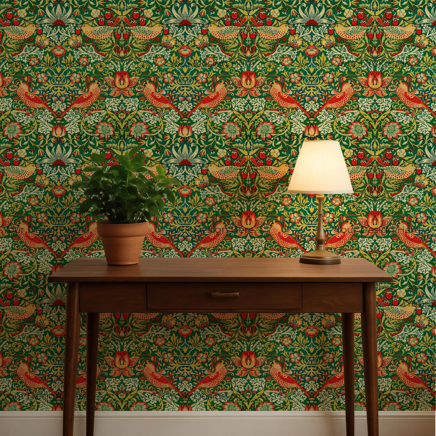 William Morris Strawberry Thief green wallpaper behind a wood console with a lamp and plant