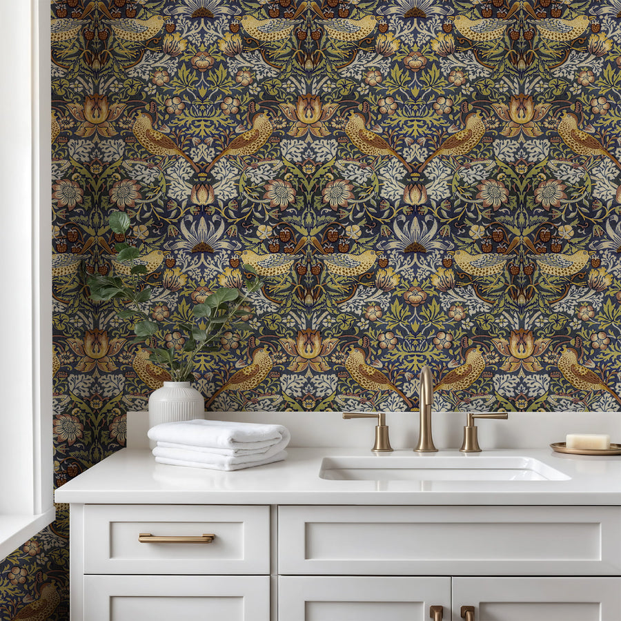 William Morris Strawberry Thief navy wallpaper in a bathroom with a white vanity and brass fixtures